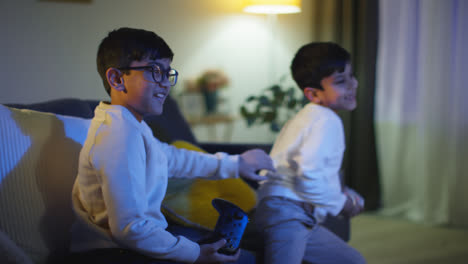 Dos-Niños-Pequeños-En-Casa-Divirtiéndose-Jugando-Con-La-Consola-De-Juegos-De-Computadora-En-La-Televisión-Peleando-Por-Los-Controladores-A-Altas-Horas-De-La-Noche-7